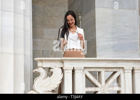 Vivacious young woman laughing at a good joke on her smart pone Stock Photo