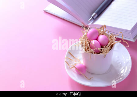 Small pink candy eggs in the cup. Easter celebrate concept. Pink background. Almonds in sugar coating. Copy space. Stock Photo