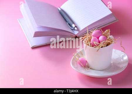 Small pink candy eggs in the cup. Easter celebrate concept. Pink background. Almonds in sugar coating. Copy space. Stock Photo