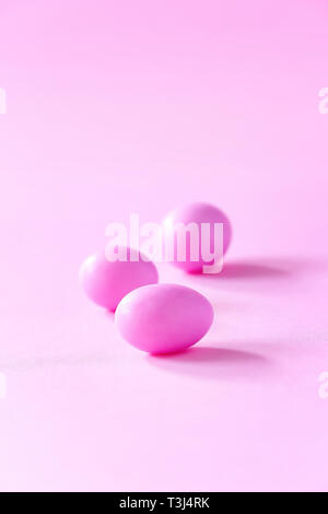Three small pink eggs on pink background. Easter celebrate concept. Copy space. Stock Photo