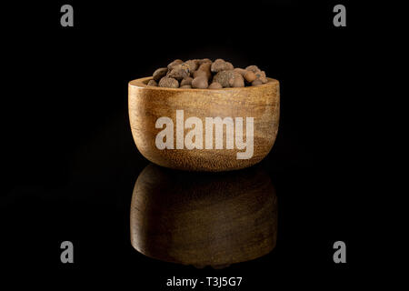 Lot of whole brown clay pebbles (leca) with wooden bowl isolated on black glass Stock Photo