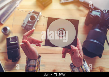 Photographer holding dvd disc with archived photos in photography studio Stock Photo