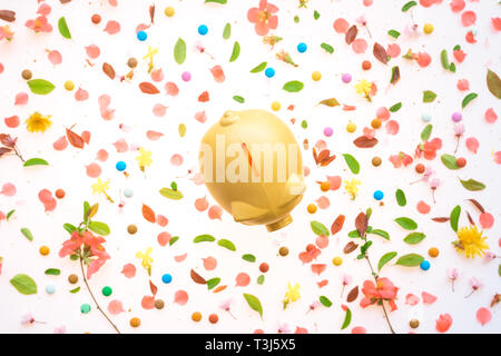 Piggy coin bank and springtime floral decoration, flat lay top view Stock Photo