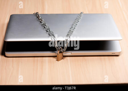 Heavy chain with a padlock around a laptop on table. Stock Photo