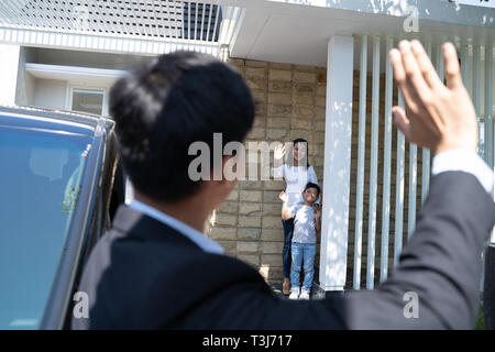 husband waving goodbye to his family before going to work Stock Photo