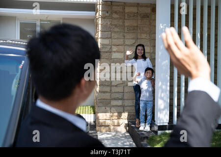 husband waving goodbye to his family before going to work Stock Photo