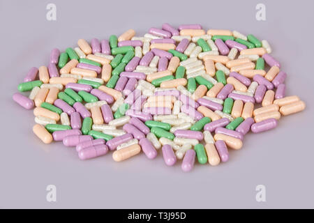Spilled different capsules on the white background. Vitamin supplements tablets Stock Photo