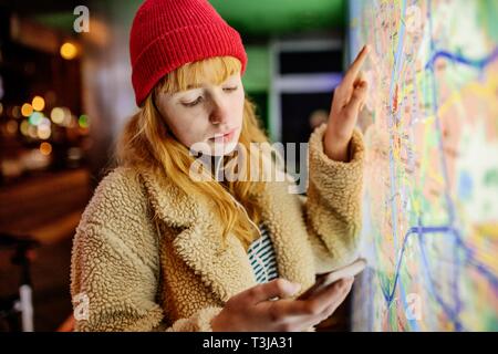 Girl, teenager, with smartphone in her hand standing at night in the city in front of city map, Cologne, North Rhine-Westphalia, Germany Stock Photo