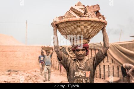 Brickyard worker carrying bricks in a basket on his head, Dhaka, Bangladesh Stock Photo