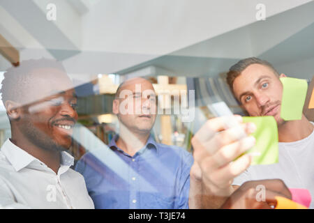 Business start-up team writes project ideas on note in brainstorming workshop Stock Photo