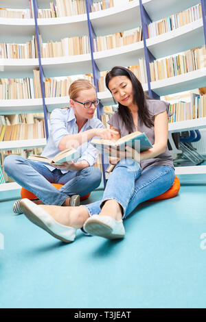 Two young women reading the book in the university library or community college Stock Photo