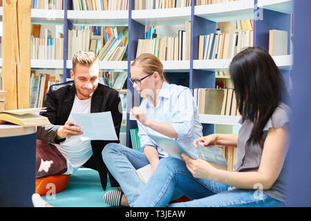 Three students in a study group study together in the university library Stock Photo