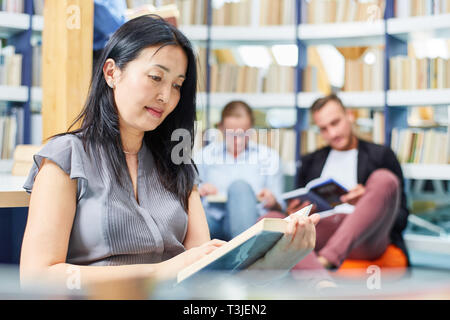 Young woman as a student reading the book in the reading room of the library in the university Stock Photo