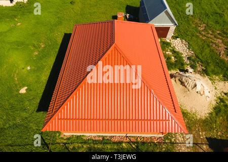 House with an orange roof made of metal, top view. Metallic profile painted corrugated on the roof Stock Photo