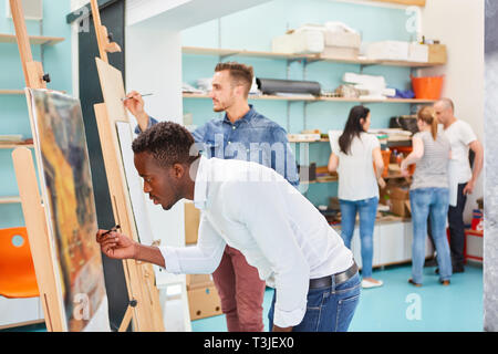 Young art students paint together on canvas at easel in art class Stock Photo