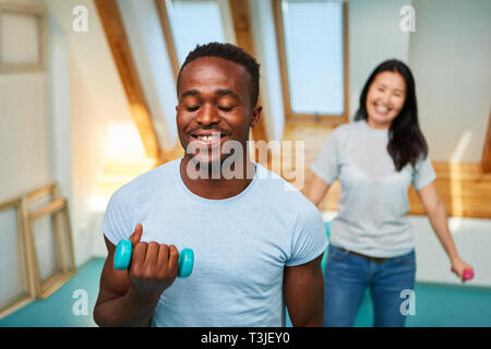 Multicultural couple doing dumbbell training for toning and healthy fitness Stock Photo