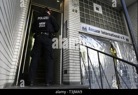 10 April 2019, North Rhine-Westphalia, Düsseldorf: A police officer is standing in front of the Ansaar International building in Düsseldorf. On Wednesday, the police will raid nine federal states against institutions of a nationwide Islamic network. Photo: Martin Gerten/dpa Stock Photo