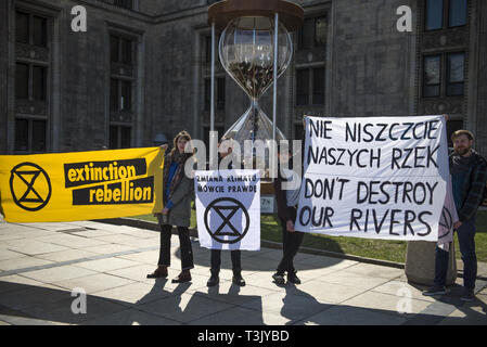 Warsaw, Mazowieckie, Poland. 10th Apr, 2019. Activists from Extinction Rebellion are seen holding banners outside the building where the Water Expo conference was held.During the Water Expo Poland International Exhibition and Conference, a group of ecological activists from Extinction Rebellion unexpectedly stripped off to highlight how dangerous for the environment is building canals and waterways on rivers. Water Expo is Poland's only exhibition and conference event to comprehensively cover all aspects of investments linked to inland waters. (Credit Image: © Attila Husejnow/SOPA Images Stock Photo