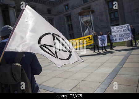 Warsaw, Mazowieckie, Poland. 10th Apr, 2019. An activist seen holding the Extinction Rebellion flag during the exhibition and conference. During the Water Expo Poland International Exhibition and Conference, a group of ecological activists from Extinction Rebellion unexpectedly stripped off to highlight how dangerous for the environment is building canals and waterways on rivers. Water Expo is Poland's only exhibition and conference event to comprehensively cover all aspects of investments linked to inland waters. Credit: Attila Husejnow/SOPA Images/ZUMA Wire/Alamy Live News Stock Photo