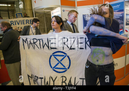 Warsaw, Mazowieckie, Poland. 10th Apr, 2019. An activist from the Extinction Rebellion group is seen taking off her shirt during the exhibition and conference. During the Water Expo Poland International Exhibition and Conference, a group of ecological activists from Extinction Rebellion unexpectedly stripped off to highlight how dangerous for the environment is building canals and waterways on rivers. Water Expo is Poland's only exhibition and conference event to comprehensively cover all aspects of investments linked to inland waters. (Credit Image: © Attila Husejnow/SOPA Images via ZUM Stock Photo