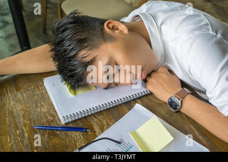 Young Asian man falling asleep on document Stock Photo