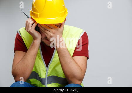 Photo of unhappy builder man in yellow helmet with walkie-talkie. Stock Photo