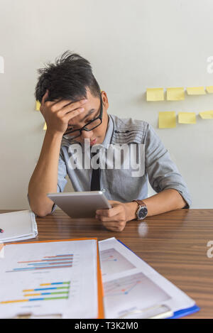 Disappointed businessman looking at negative results on the tablet Stock Photo