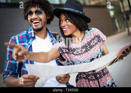 Happy young african couple of travellers holding map in hands Stock Photo