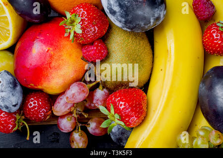 many different mixed seasonal ripe juicy fruits on dark background , concept of healthy and proper nutrition, snack, top view, copy space Stock Photo