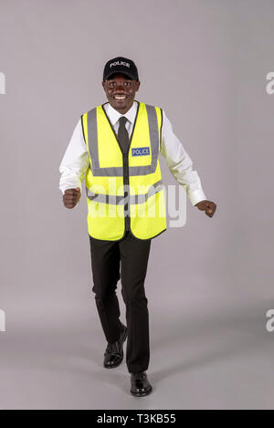 Portrait of a smiling police officer in uniform walking toward the camera. Stock Photo