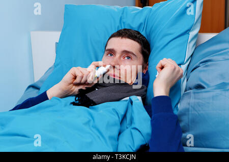 Image of sick man using nasal spray while lying in bed Stock Photo