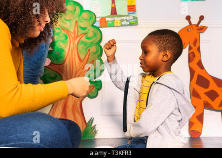 Teacher and little boy play rock paper scissors Stock Photo