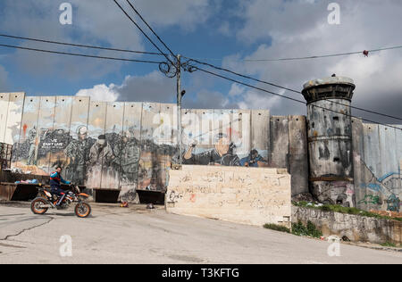 A Palestinian teenager rides his motorbike past the security wall in Aida Camp, Bethlehem, West Bank, Palestine, 11/02/19 Stock Photo