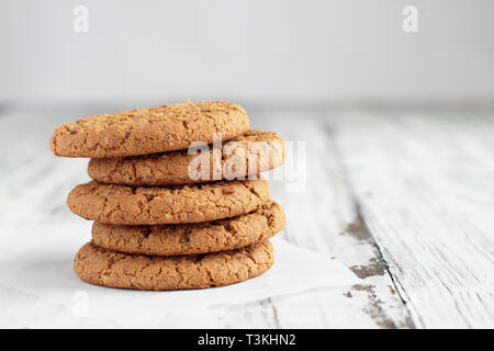 Stack of fresh homemade oatmeal cookies with a bottle of milk on a white table against a white background.. Stock Photo