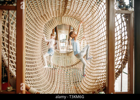 Girls climbing the rope net, children game center Stock Photo