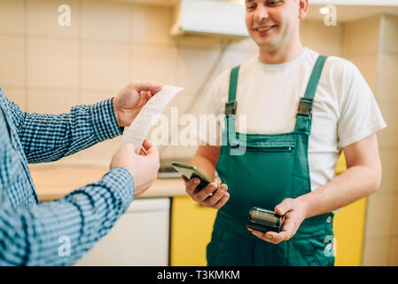 Repairman in uniform gives the check to the client Stock Photo