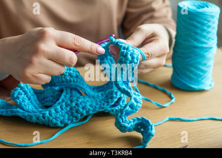 knitting pink crochet hooks and woolen thread on a blue background