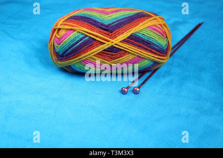 Knitting Needles with a Ball of Wool on a Blue Background Stock Photo