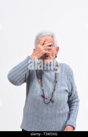 senior woman peeking with hand on face on white background Stock Photo