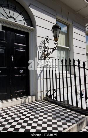 Front door of gentrified London house with black and white tiled entrance step and railings to side Stock Photo