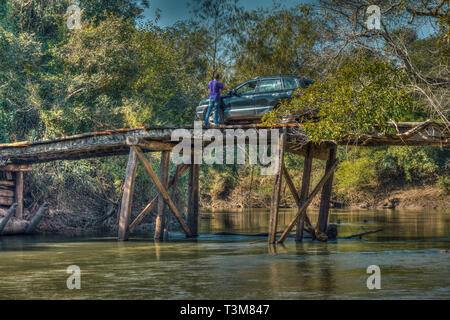 Tourist with car on a large, rickety wooden bridge in the middle of the wilderness of Paraguay. Stock Photo