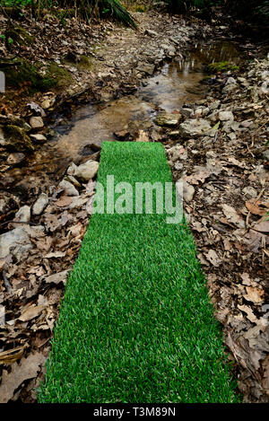 Artificial green plastic grass carpet by the river Stock Photo