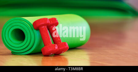 green sports mat for physical activities and dumbbells on the floor Stock Photo