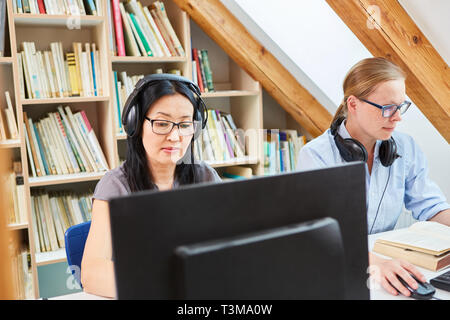 Two women are doing e-learning language course or working together in co-working office Stock Photo