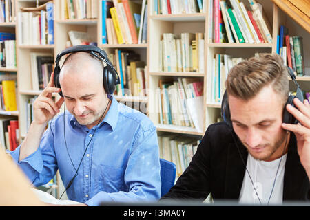 Two young men with headphones in a folk high school e-learning language course Stock Photo