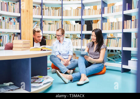 Three students study group and tablet computer while learning in the library Stock Photo