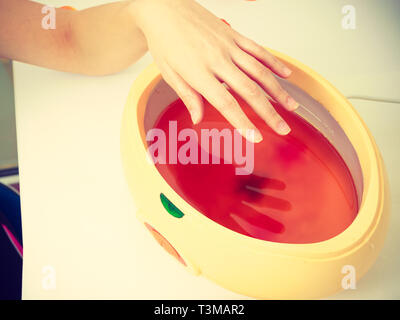 Handcare, beauty studio wellness treatments concept. Woman getting paraffin hand treatment at spa salon. Stock Photo