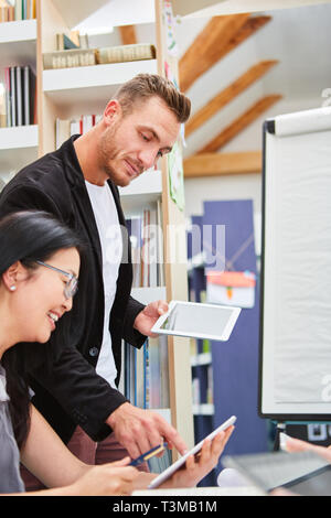 Teacher using tablet computer online helps a student on internet course or workshop Stock Photo