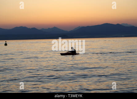 Lonely paddler on the lake during the sunset Stock Photo