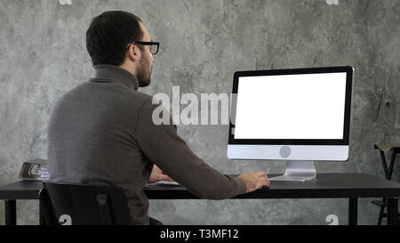 Bearded young businessman woking on computer. White Display. Stock Photo